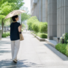 ベージュの晴雨兼用日傘をさして夏の街を歩く女性