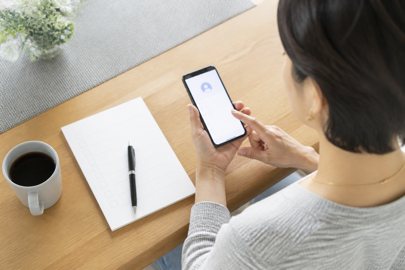 送付先を確認するためスマートフォンを見る女性の手元
