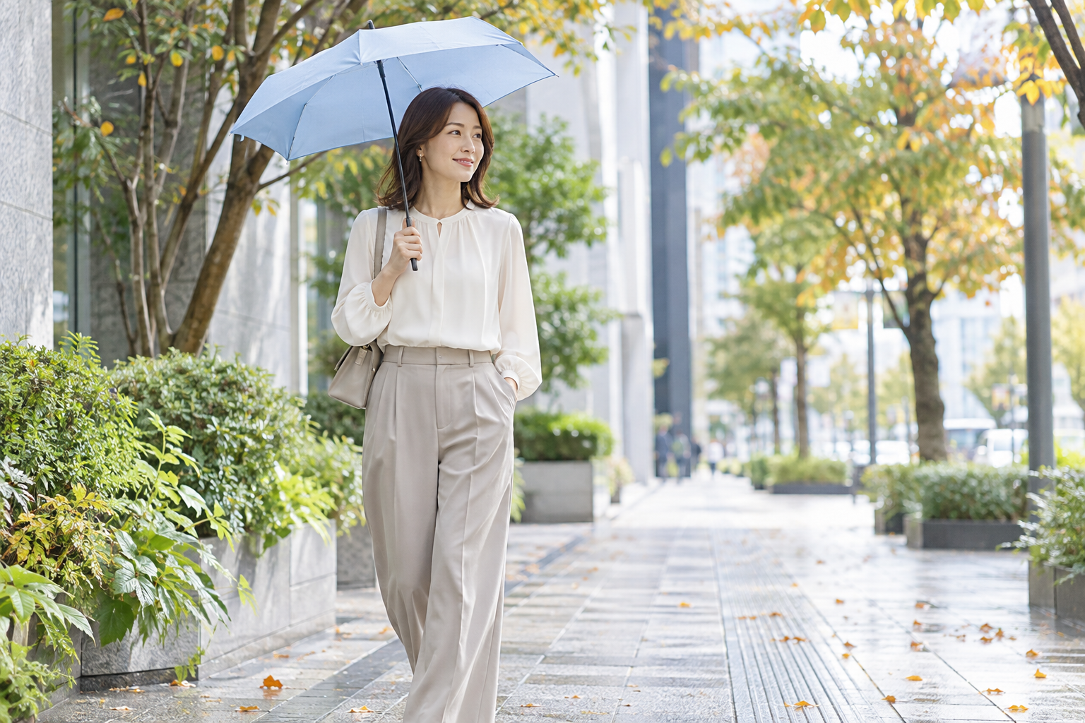 秋の街並みで淡いブルーの折りたたみ傘を持つ女性