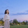 夕暮れの公園で秋の空を見上げる女性