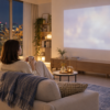 夜のリビングでソファに座り映画を楽しむアイボリーのニットの女性