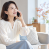 明るいリビングで家族へ電話をかける女性と秋の花