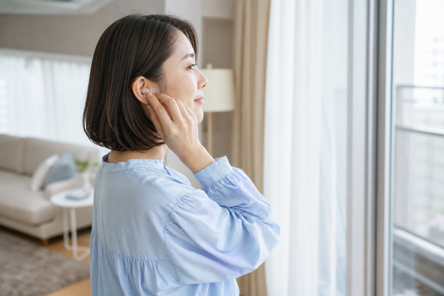 窓際で小さなライブ用耳栓を耳に合わせる女性